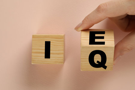 Woman turning cube with letters E and I near Q on beige background, top viewの写真素材