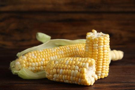 Tasty sweet corn cobs on wooden table, closeup