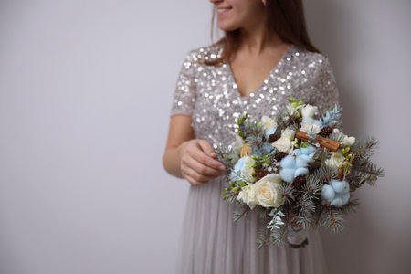 Bride holding beautiful winter wedding bouquet on light gray background, closeup. Space for textの写真素材