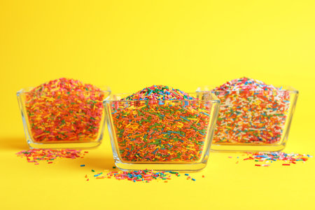 Colorful sprinkles in bowls on yellow background. Confectionery decorの写真素材