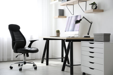 Comfortable office chair near table with modern computerの写真素材