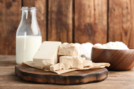 Pieces of compressed yeast near ingredients for dough on wooden tableの写真素材