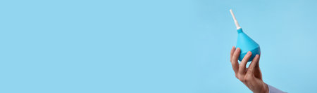 Man holding enema on light blue background, closeupの写真素材