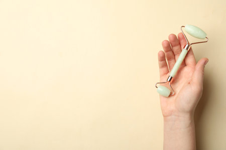 Woman with natural face roller on beige background, top view. Space for textの写真素材