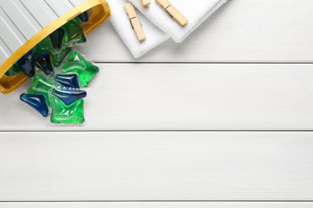 Laundry capsules on white wooden table, flat lay. Space for text