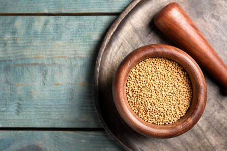 Pestle and mortar with mustard seeds on wooden table, flat lay. Space for textの写真素材