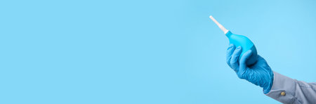 Man holding enema on light blue background, closeupの写真素材