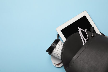 Stylish urban backpack with different items on light blue background, top view. Space for textの写真素材