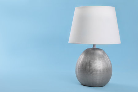 Stylish new night lamp on light blue background. Space for textの写真素材