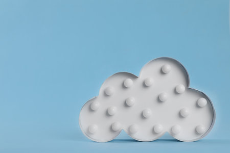 Stylish cloud shaped night lamp on light blue background. Space for textの写真素材