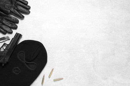 Flat lay composition with balaclava and weapons on light table. Space for textの写真素材