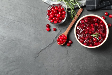 Flat lay composition with cranberry sauce and fresh berries on dark gray table. Space for textの写真素材