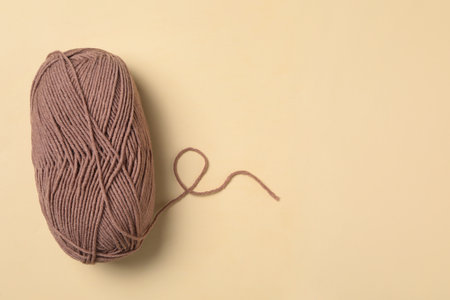 Soft brown wool yarn on beige background, top view. Space for textの写真素材