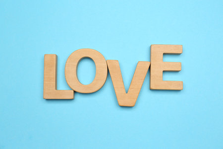 Word LOVE made of wooden letters on light blue background, flat layの写真素材
