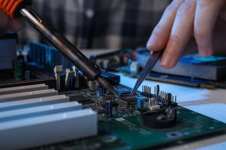 Technician repairing electronic circuit board with soldering iron at table, closeupの写真素材