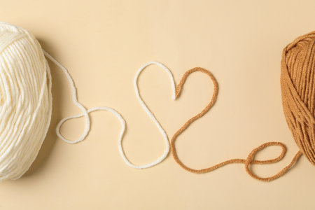 Heart made with threads and woolen yarns on beige background, flat layの写真素材
