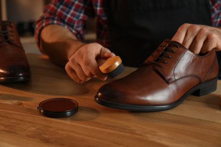Craftsman taking professional care of brown leather shoes in workshop, closeupの写真素材