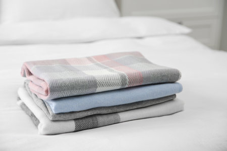 Stack of folded cashmere clothes on bed