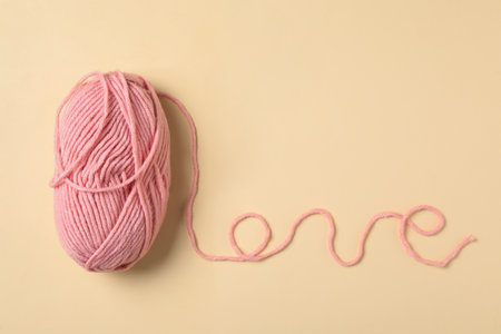 Word Love made with pink thread and woolen yarn on beige background, top view. Space for textの写真素材