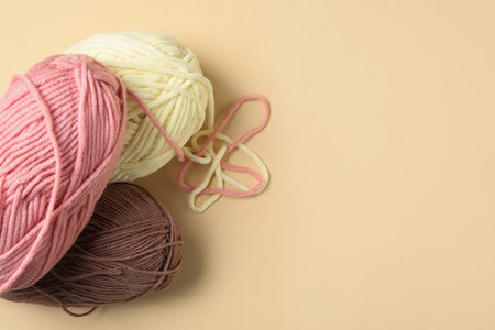 Soft woolen yarns on beige background, flat lay. Space for textの写真素材