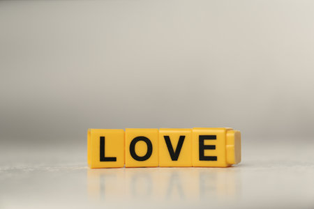 Word Love made of yellow cubes with letters on light tableの写真素材