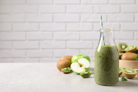 Delicious kiwi smoothie and fresh fruits on light table. Space for textの写真素材