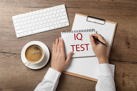 IQ test. Woman with pen and notebook at wooden table, top viewの写真素材