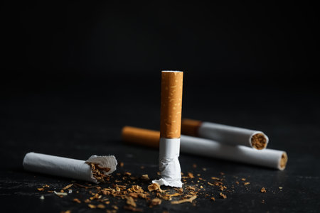 Broken and whole cigarettes on black table, closeup. Quitting smoking conceptの写真素材