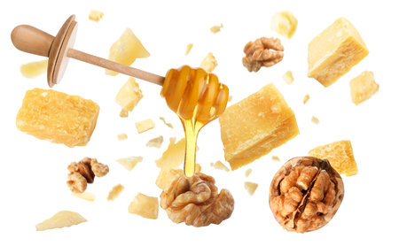 Pieces of delicious parmesan, walnuts and honey falling on white backgroundの写真素材