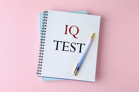 Notebook with text IQ Test and pen on pink background, top viewの写真素材
