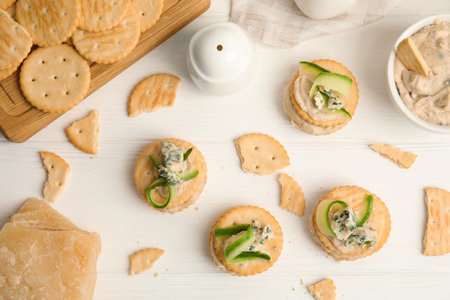 Delicious crackers with humus and cucumber on white wooden table, flat layの写真素材