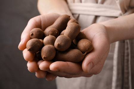 Woman holding fresh ripe tamarinds, closeup viewの写真素材