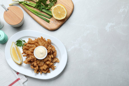 Delicious onion blossom served with lemon and sauce on white table, flat lay. Space for textの写真素材