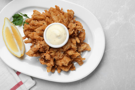 Delicious onion blossom served with lemon and sauce on white table, flat layの写真素材