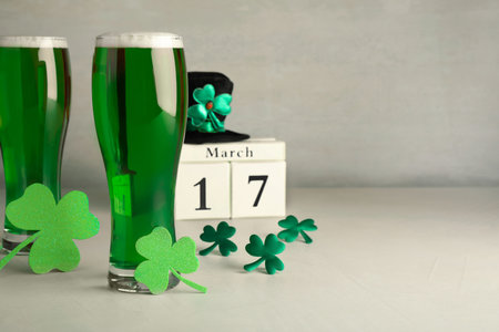 Green beer and St Patrick's Day decor on light table. Space for text