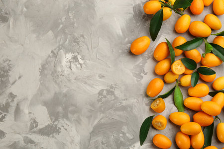 Fresh ripe kumquats on light gray table, flat lay. Space for textの写真素材