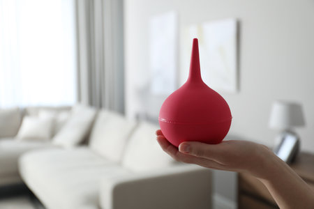 Woman holding pink enema at home, closeup. Space for textの写真素材