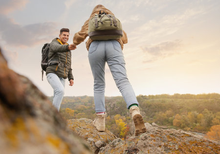 Couple of hikers with backpacks climbing up mountainsの写真素材