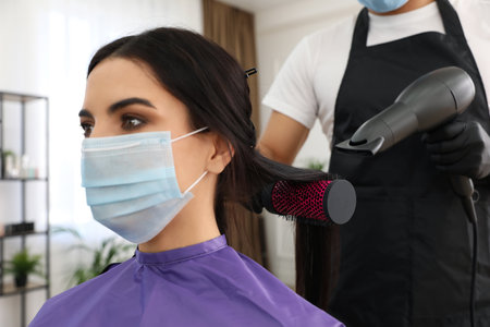 Professional stylist working with client in salon, closeup. Hairdressing services during Coronavirus quarantineの写真素材
