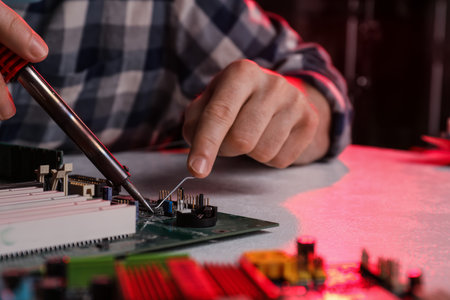 Technician repairing electronic circuit board with soldering iron at table, closeupの写真素材