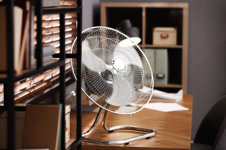 Modern electric fan on table in officeの写真素材