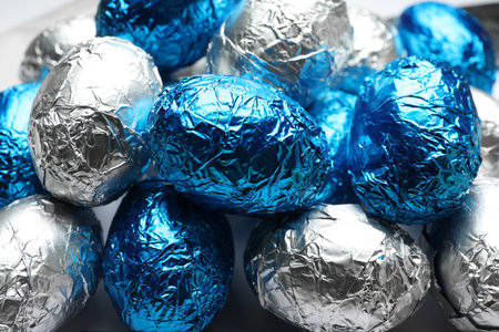 Chocolate eggs wrapped in blue and silver foil as background, closeupの写真素材