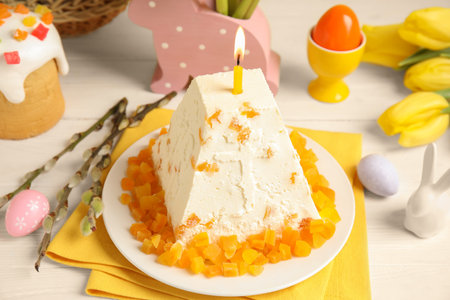 Traditional cottage cheese Easter paskha with dried apricot and burning candle on white wooden table
