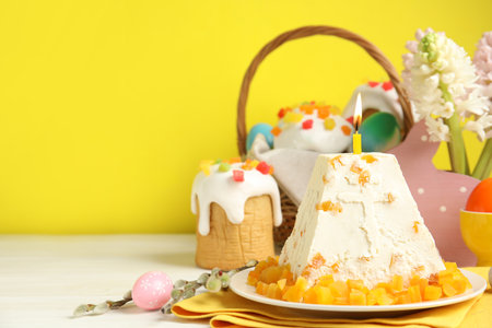 Traditional cottage cheese Easter paskha with dried apricot and burning candle on white wooden...