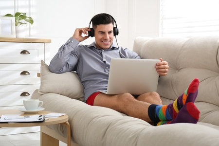 Businessman in shirt and underwear working on laptop at homeの写真素材