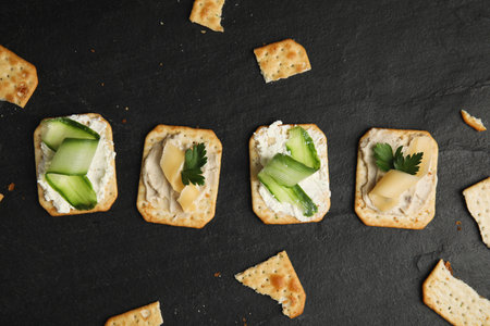 Delicious crackers with humus and cheese on black table, flat layの写真素材