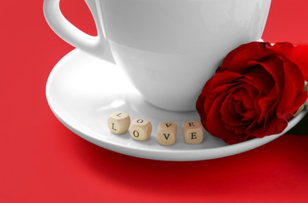 Cup of coffee, mini cubes with word LOVE and rose on red background, closeupの写真素材