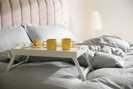 Soft blanket and tray with breakfast on bed indoorsの写真素材