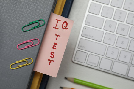 Paper with words IQ Test in notebook, keyboard and fasteners on office table, flat layの写真素材