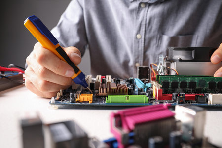 Technician repairing electronic circuit board at table, closeupの写真素材